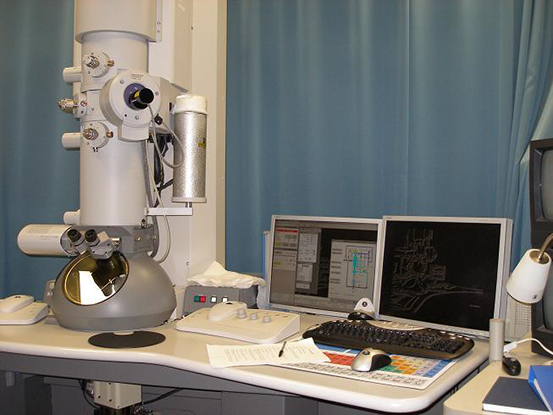 A transmission electron microscope on a desk beside a computer.